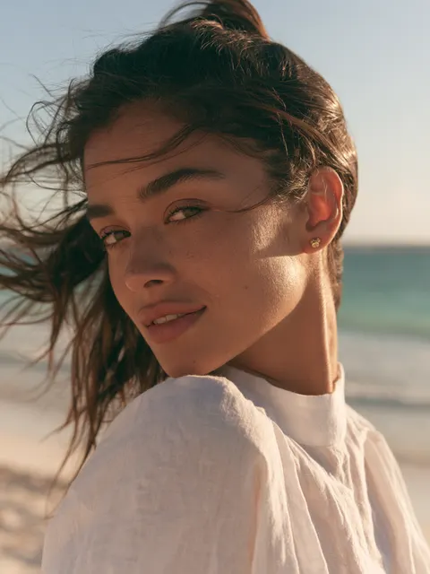 Imagen ilustrativa de otoplastia: modelo en la playa al atardecer